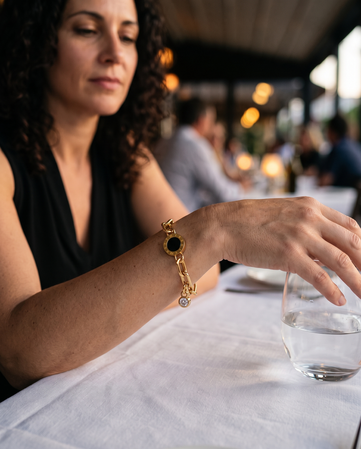 Roman Disc Bracelet worn on the wrist at a restaurant table in the early evening