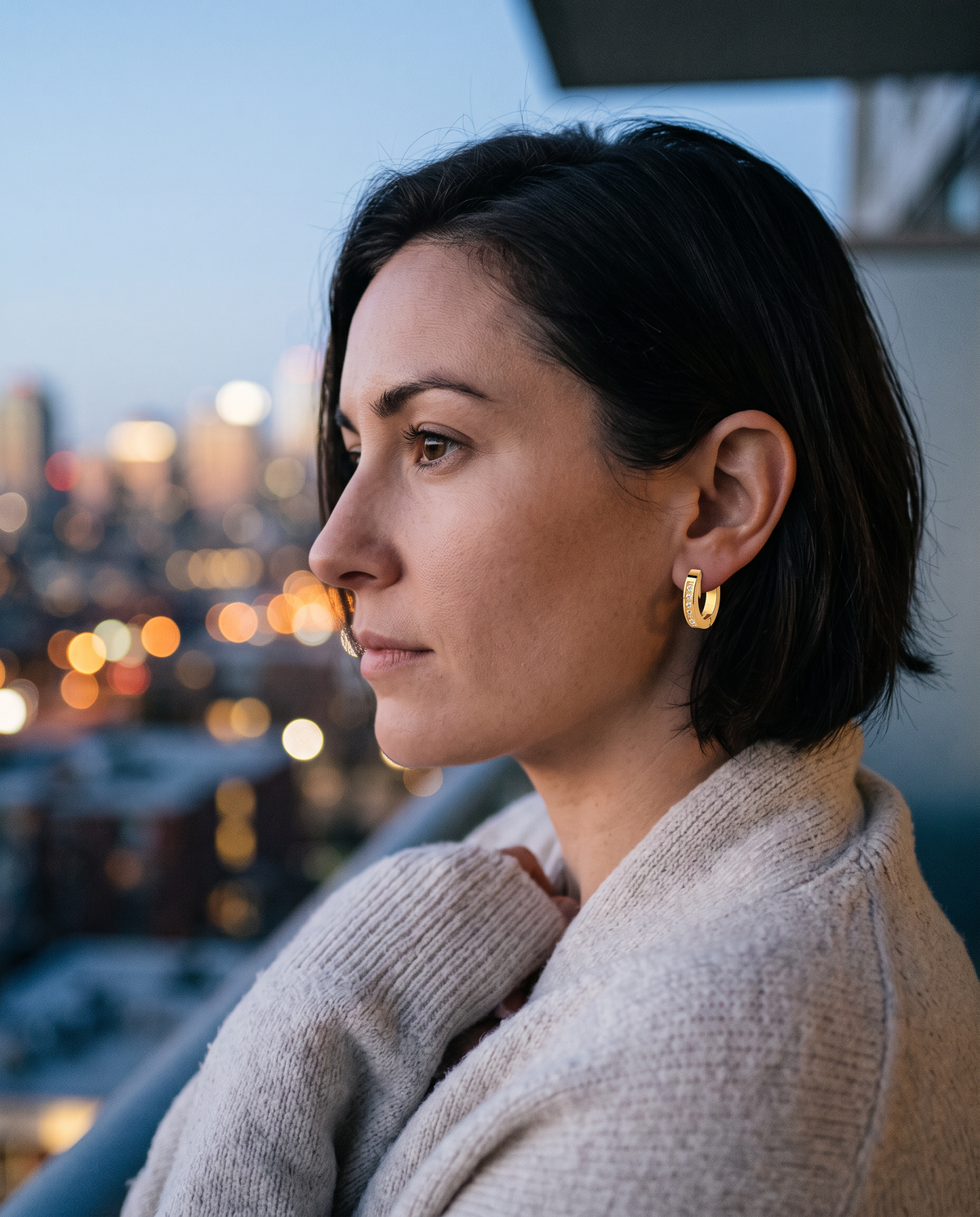 Pave Huggie Hoops worn on the ear on a balcony at dusk